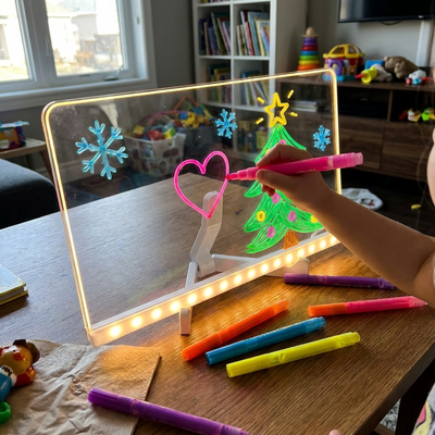 Child's hand drawing on the clear board with a pink marker